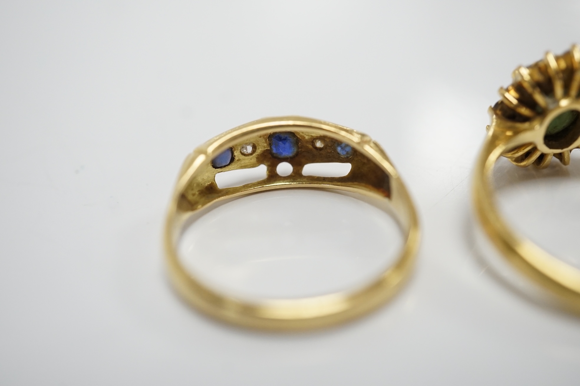 Two yellow metal and gem set rings, including a sapphire? and diamond oval cluster and a three stone sapphire and two stone diamond half hoop, gross weight 7.3 grams. Condition - poor to fair